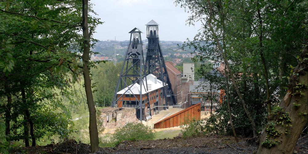 Sur la photo : la houillère du Bois du Cazier depuis le terril. Les voyageurs trouveront une lentille singulière qui magnifie le monde minier au cours des XIXe et XXe siècles. – © Photo-Daylight