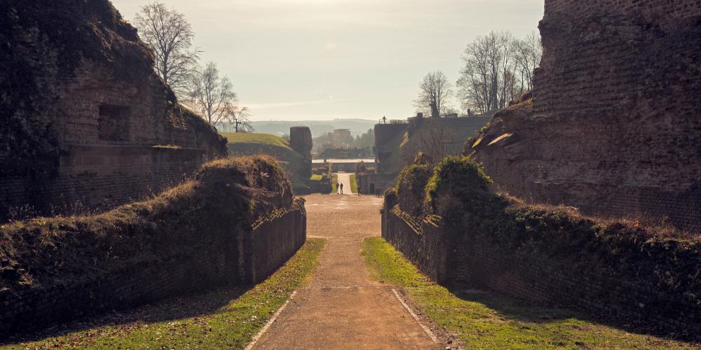 L'entrée nord de l'Amphithéâtre. L'arène est entourée d'un mur de protection avec des ouvertures pour les cages d'animaux. – © Thomas Zühmer L'entrée nord de l'Amphithéâtre. L'arène est entourée d'un mur de protection avec des ouvertures pour les cages d'animaux. – © Thomas Zühmer