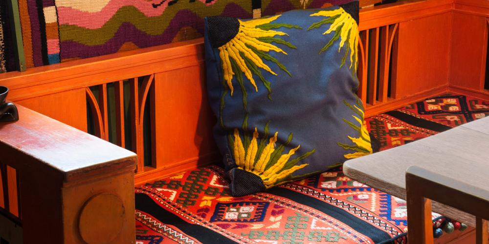 Le canapé de la salle à manger est décoré du « coussin tournesol » de Karin. Au-dessus, la tapisserie « Les quatre éléments » est un exemple des tissages audacieux de Karin. – © Carl Larsson-gården