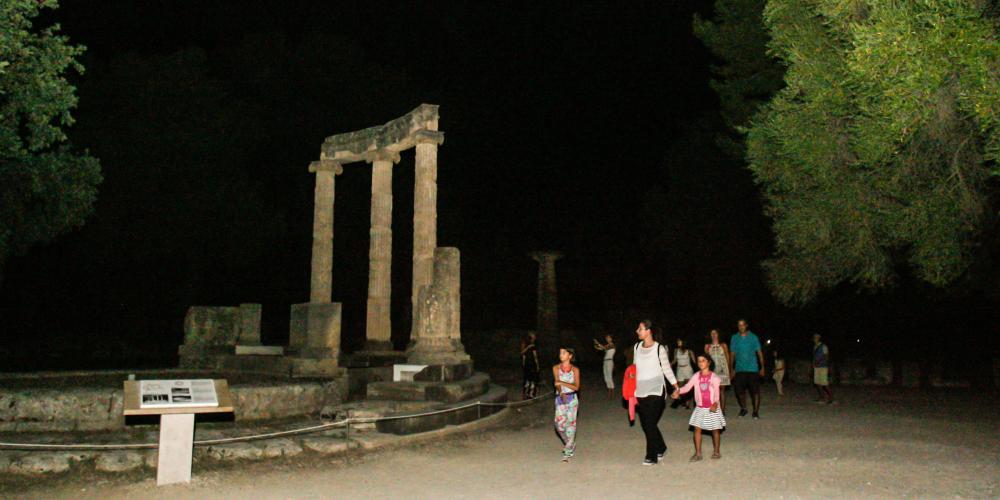 Visitors passing by the Philippeion as they enjoy a night stroll in the archaeological site of Olympia. – © Giannis Spyrounis / www.ilialive.gr
