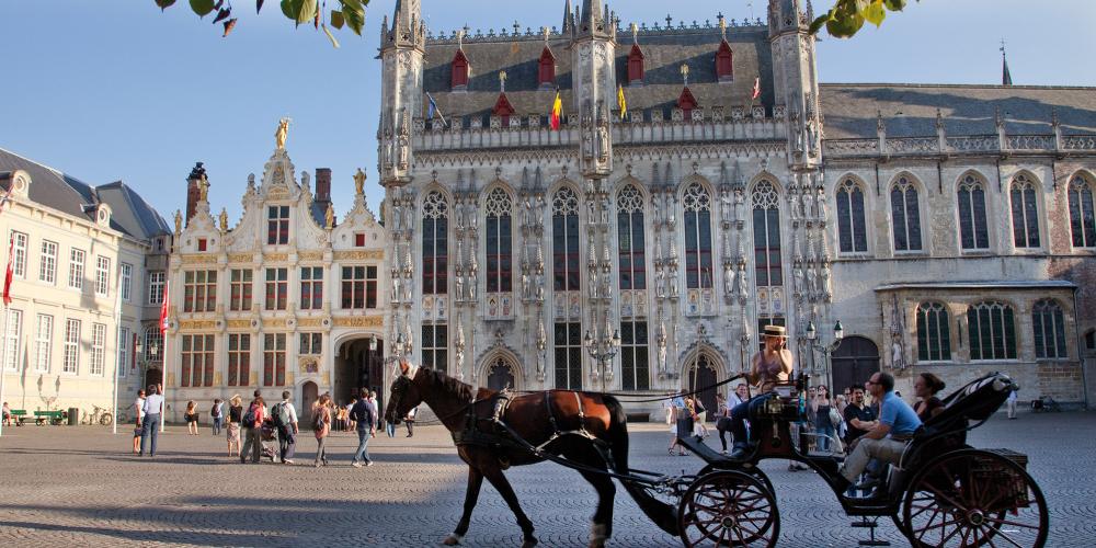 Take in Burg Square at a relaxed speed with a horse-drawn carriage tour. – © Jan D'Hondt / VisitBruges