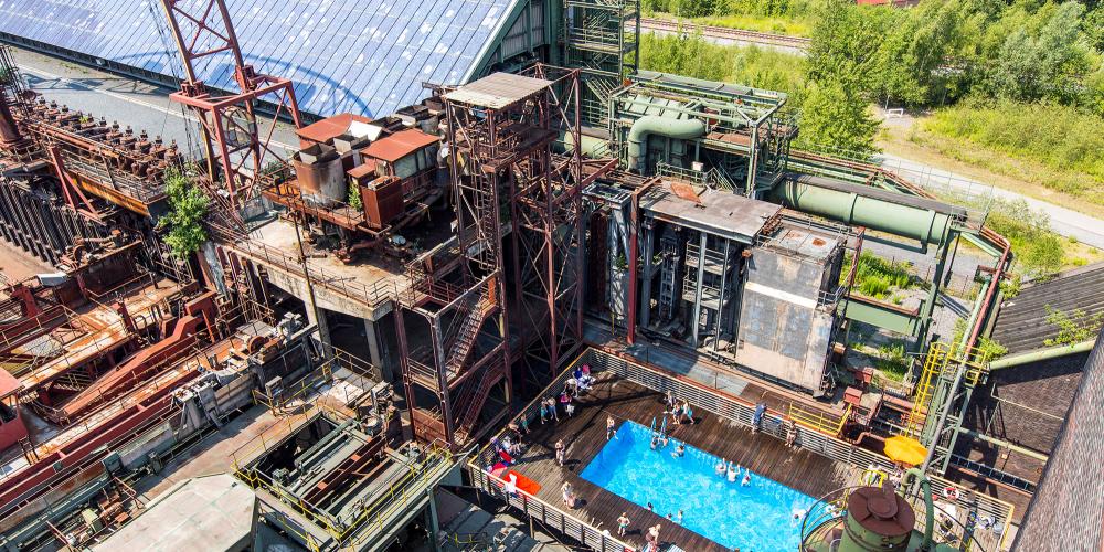 Pause baignade dans la piscine bleue au milieu de l'ancienne cokerie : lorsque la météo est au beau fixe, vous pouvez vous rafraîchir, prendre un bain de soleil et vous détendre à la piscine tous les jours de 12h00 à 20h00 pendant les vacances d’été en Rhénanie-du-Nord-Westphalie. – © Jochen Tack / Zollverein Foundation