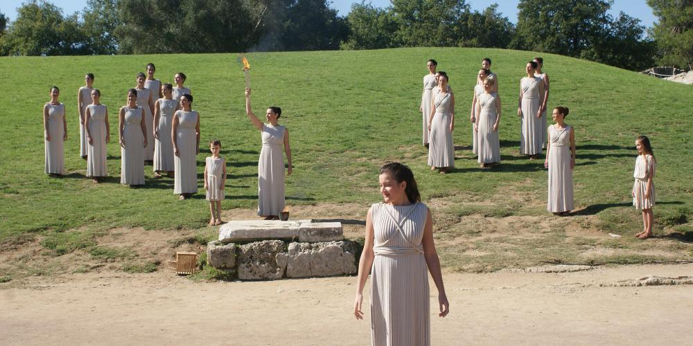 The head priestess raises the Olympic Flame moments before the torch relay begins in the Stadium. – © Hellenic Ministry of Culture and Sports / Ephorate of Antiquities of Ilia