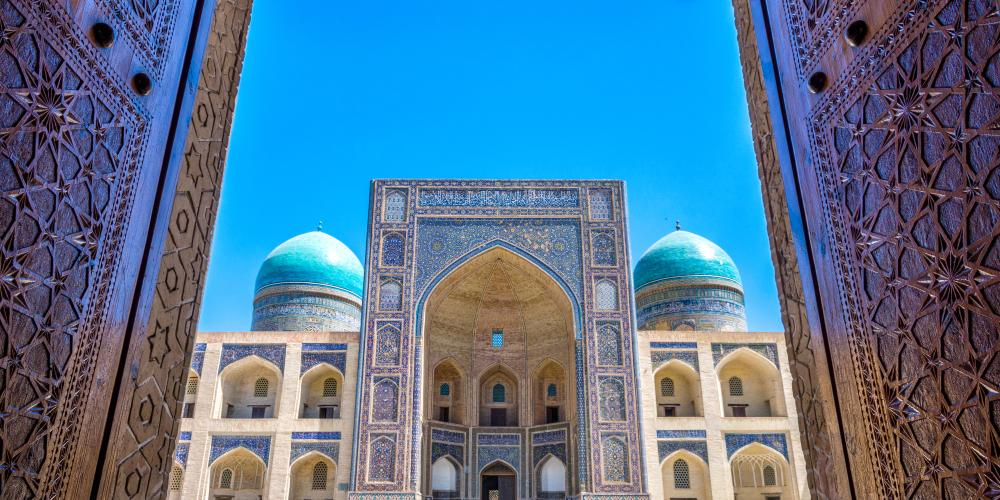 View to Mir i Arab madrassa through the old wooden carved door, Bukhara, Uzbekistan – © Ana Flasker / Shutterstock