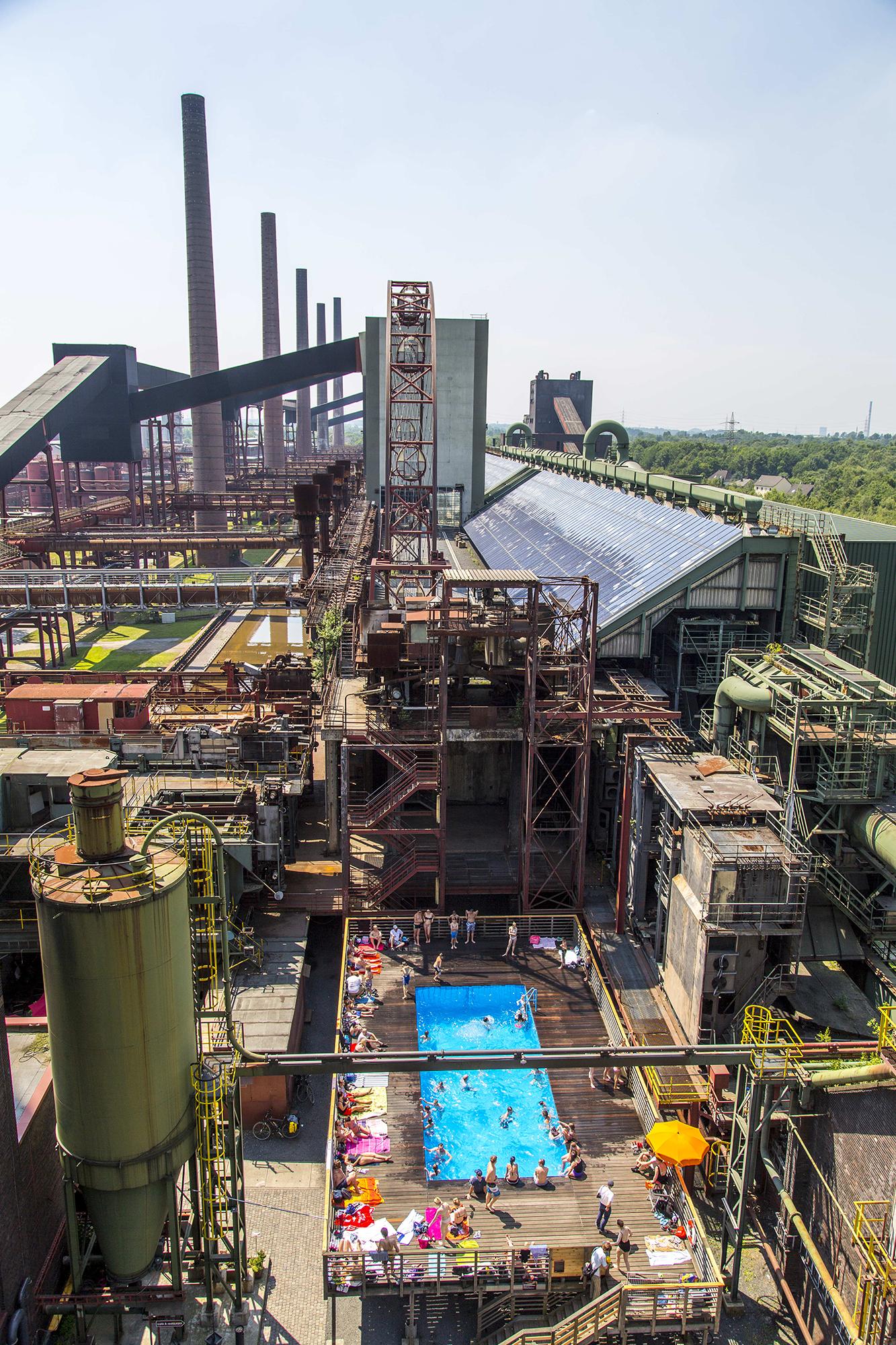 Vue aérienne de la piscine avec vue sur la longue batterie de fours à coke avec ses cheminées et son système d'énergie solaire. - Photographie de Jochen Tack, Fondation Zollverein