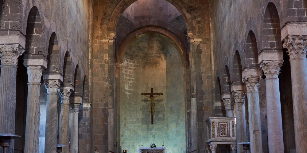 Central nave of the Romanesque Cathedral with the colonnade and the apse area. – © Emma Taricco