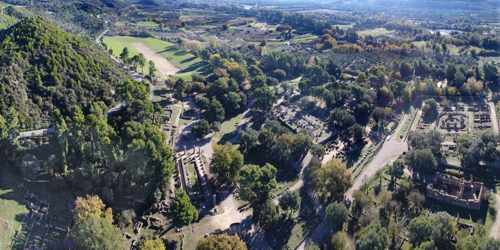 Vue du site d'Olympie avec les temples d'Héra et de Zeus au premier plan et le stade en arrière-plan. – © Ministère Hellénique de la Culture et des Sports / Ephorie des Antiquités d'Ilia (efailias) Vue du site d'Olympie avec les temples d'Héra et de Zeus au premier plan et le stade en arrière-plan. – © Ministère Hellénique de la Culture et des Sports / Ephorie des Antiquités d'Ilia (efailias)