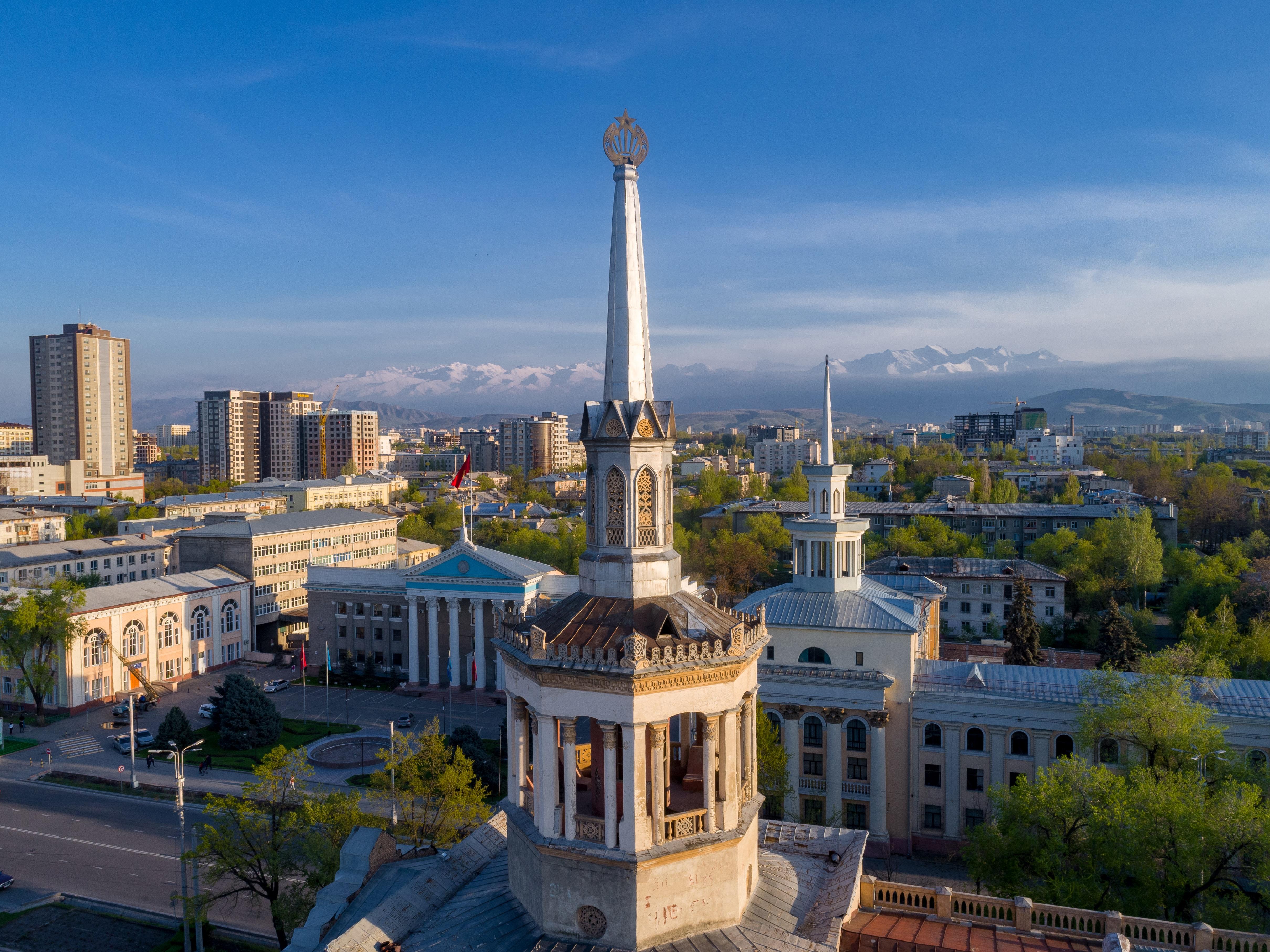 Spire on the building of International University of Kyrgyzstan in Bishkek. Tien Shan mountain range in background © Mike Dudin / Unsplash