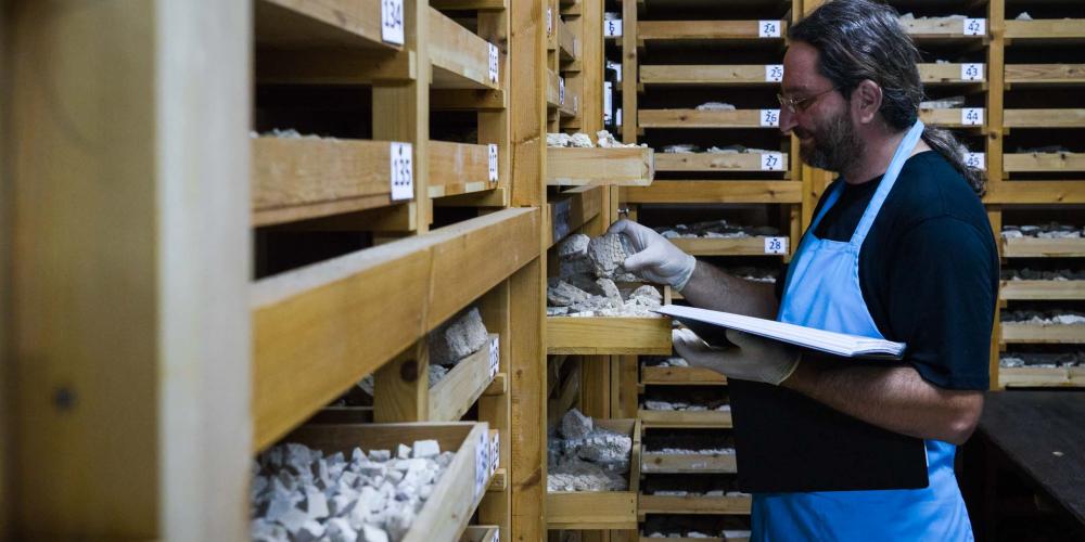 Dr. Eleftherios Charalambous, conservator at the Kato Pafos Archaeological site, looks through trays of 'tesserae', the small stones used to make the mosaics. – © Michael Turtle Dr. Eleftherios Charalambous, conservator at the Kato Pafos Archaeological site, looks through trays of 'tesserae', the small stones used to make the mosaics. – © Michael Turtle