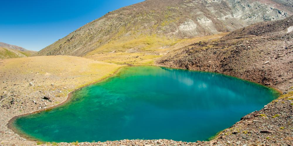 Small colorful blue green turquoise lake near Sary Chelek lake, Kyrgyzstan, Trekking in Central Asia – © Baisa / Shutterstock