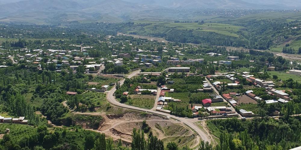 Aerial view of a suburban area in lush green landscapes and mountains in the background in Uzbekistan – Photo by Jalol Ibragimov