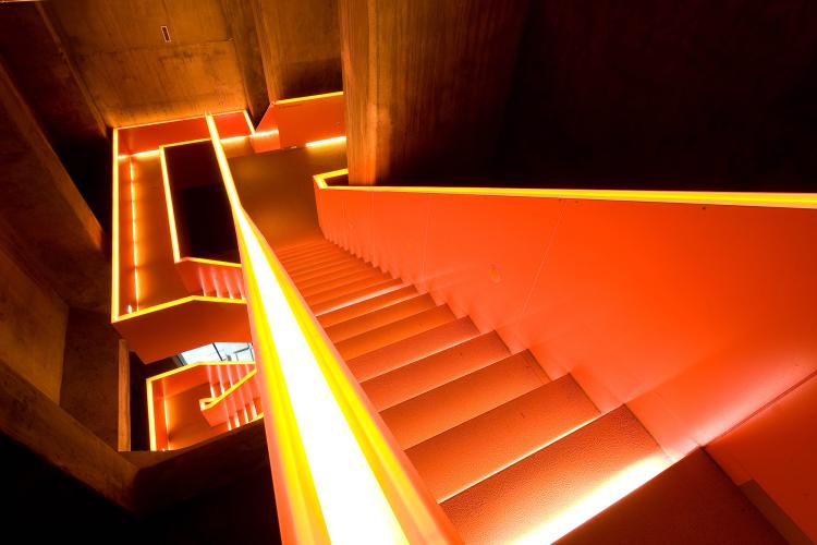 The stairwell in the coking coal bunker’s nearly 20-metre-deep shaft takes visitors to the Ruhr Museum’s exhibition levels. The orange colour marks a newly introduced element. – © Thomas Willemsen / Zollverein Foundation