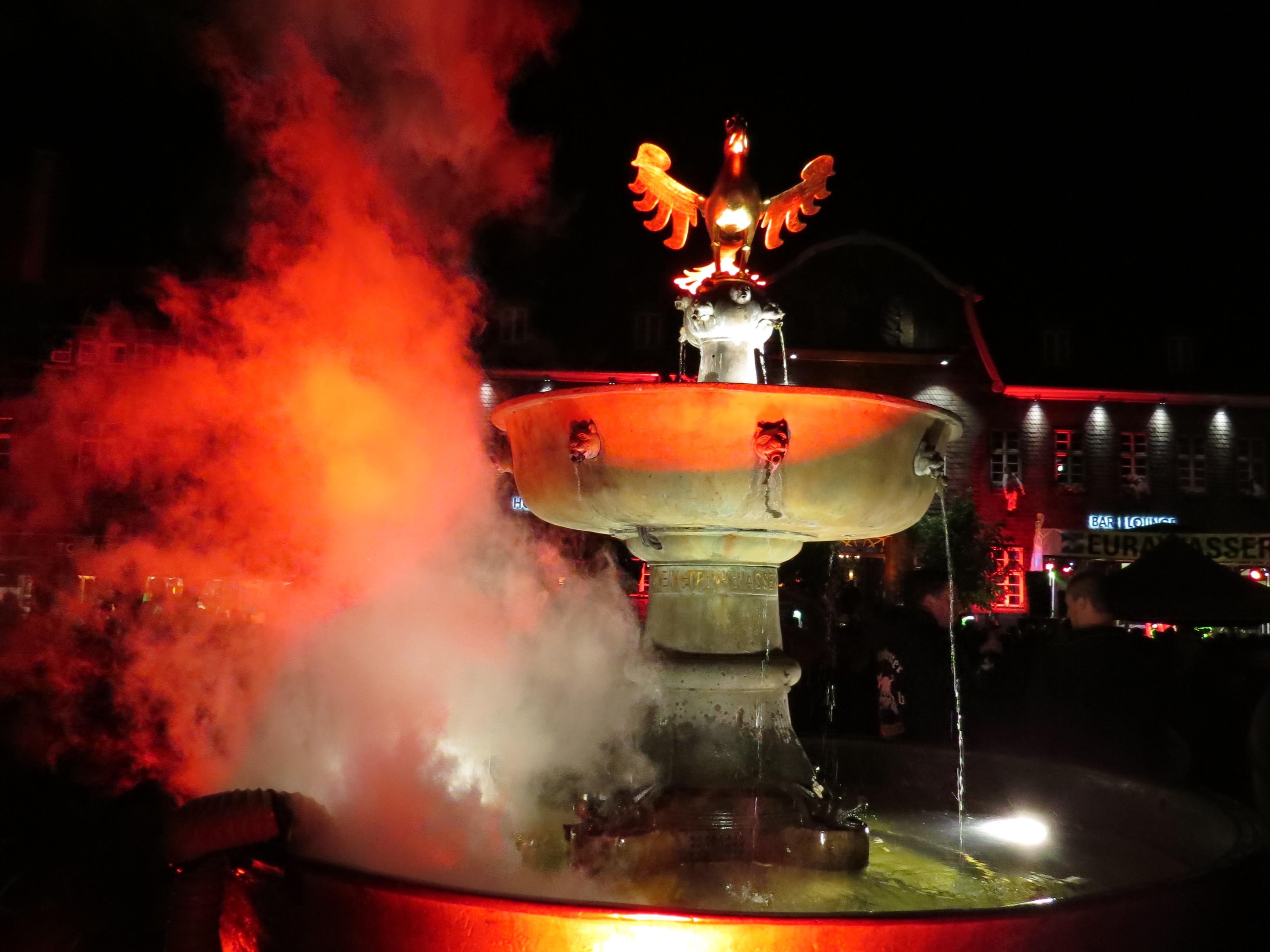 During the Walpurgis Festival, fog rises up from the red illuminated fountain and immerses the market square in a mystic atmosphere while the bands are playing. – © GOSLAR marketing gmbh