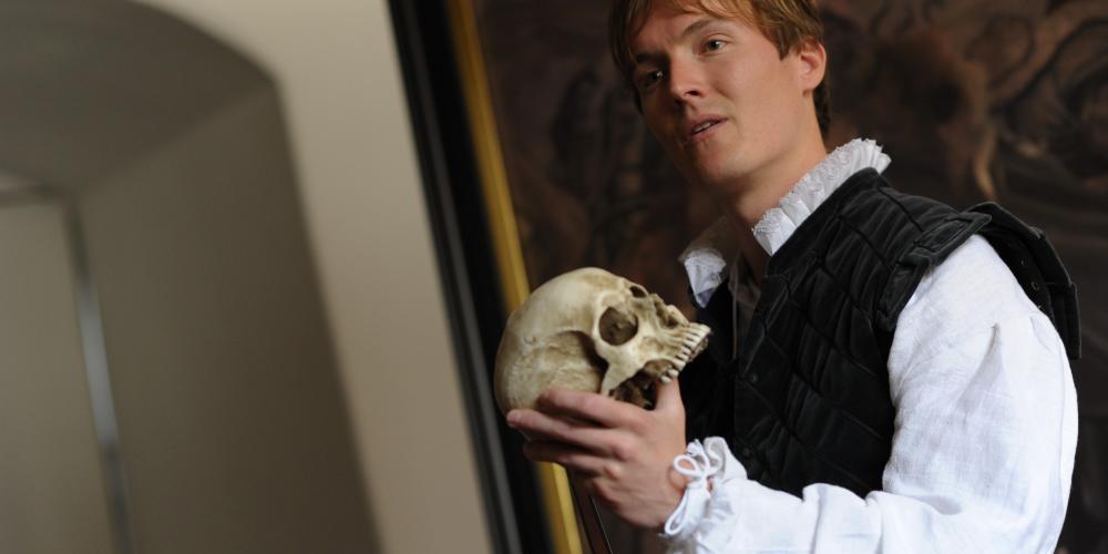 Hamlet in the iconic “to be, or not to be” scene with the skull of Yorick, his long-deceased jester. – © Tobias Fonsmark / Kronborg Slot Hamlet in the iconic “to be, or not to be” scene with the skull of Yorick, his long-deceased jester. – © Tobias Fonsmark / Kronborg Slot