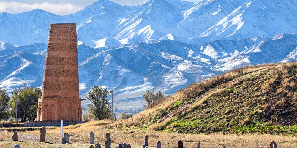 Burana tower which is an old minaret in the ruins of the ancient site of Balasagun with tombstones (balbas) in the foreground, Kyrgyzstan – © MehmetO / Shutterstock