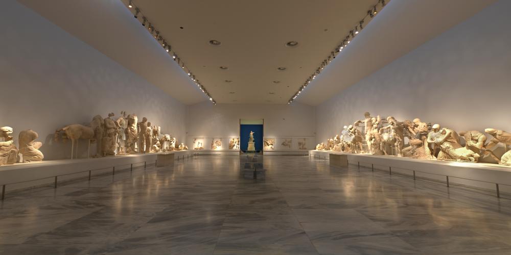 Le hall central est impressionnant avec les décorations sculpturale du temple de Zeus et la statue de la Victoire de Paionios en arrière-plan. – © Ministère Hellénique de la Culture et des Sports / Ephorie des Antiquités d'Ilia (efailias)