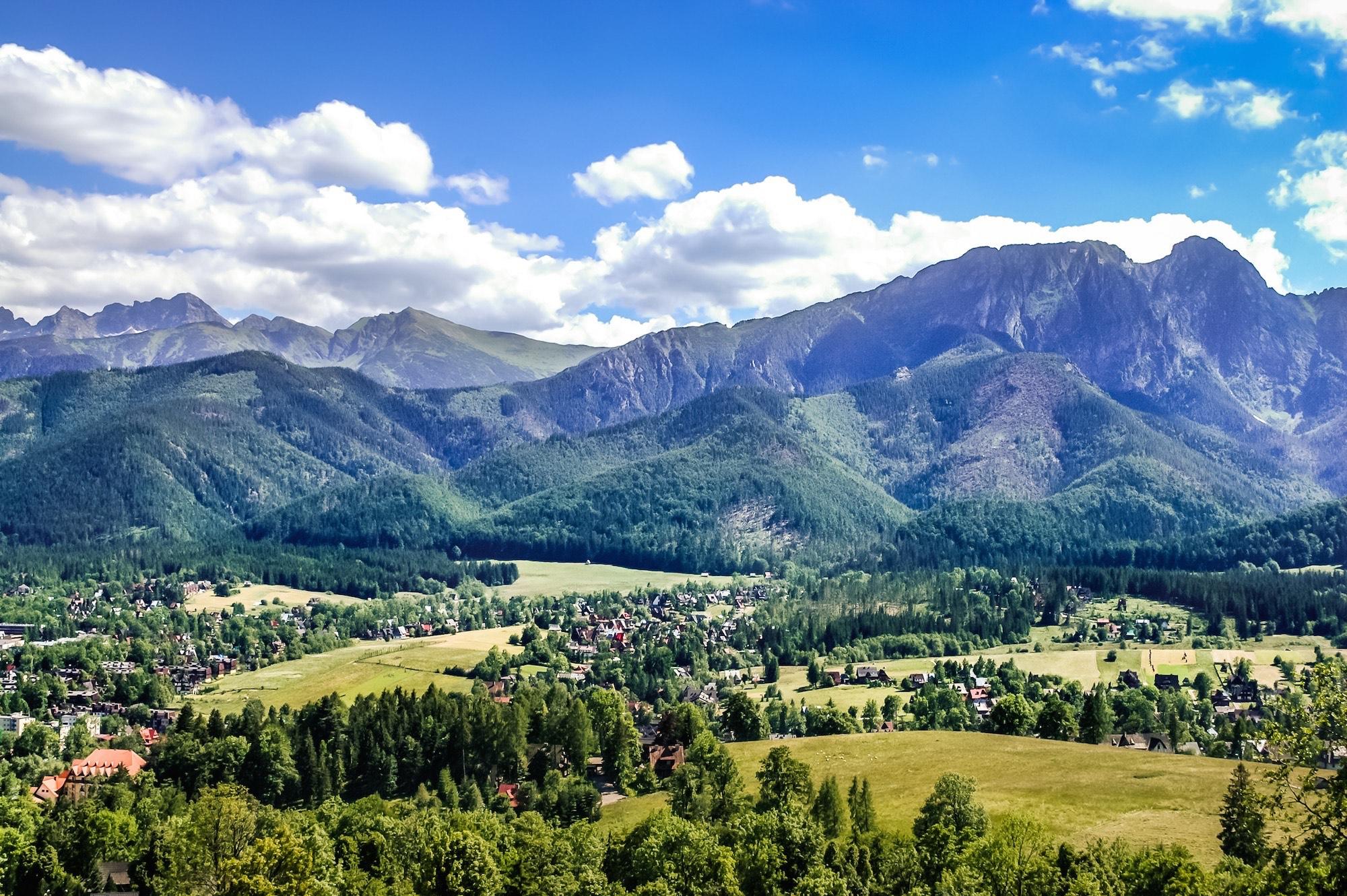 Panorama of the Western Tatra Mountains from Gubałówka with Mount Giewont in the foreground. When visiting Gubałówka, it is worth walking along the road towards Butorowy Wierch, where you'll pass souvenir stalls, highlander inns and enjoy active attractions including climbing walls, rope parks, and horse or quad riding. – © Alicja Neumiller