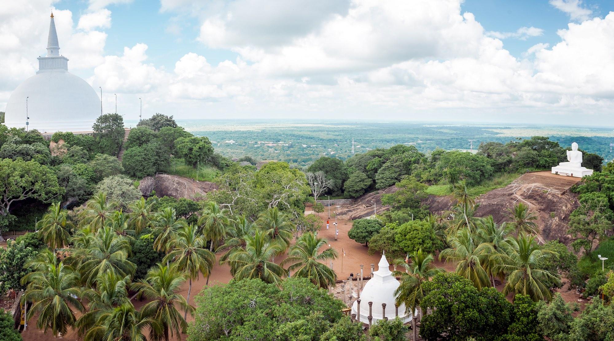 The view from Aradhana Gala Rock with Maha Seya Stupa (left), Ambasthala Stupa (center) and Buddha Statue (right) in Mihintale, the cradle of Buddhism in Sri Lanka. – © Bortoluca / Shutterstock