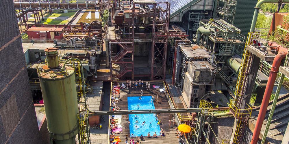 Vue aérienne de la piscine avec vue sur l'usine de mélange à gauche et la longue batterie de fours à coke avec un système d'énergie solaire. – © Jochen Tack / Zollverein Foundation