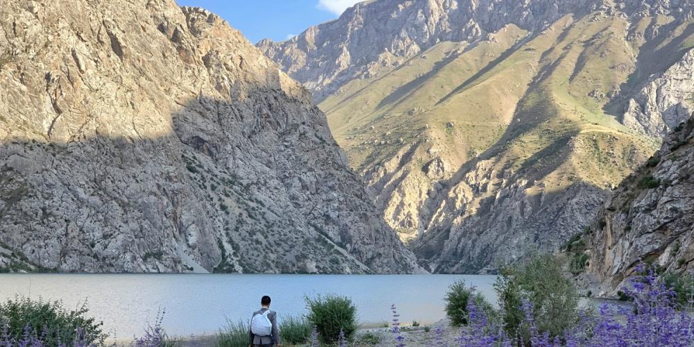 Visitor surrounded by the majestic presence of the rocky mountains in Tajik National Park. – © Tajikistan National Park Visitor surrounded by the majestic presence of the rocky mountains in Tajik National Park. – © Tajikistan National Park