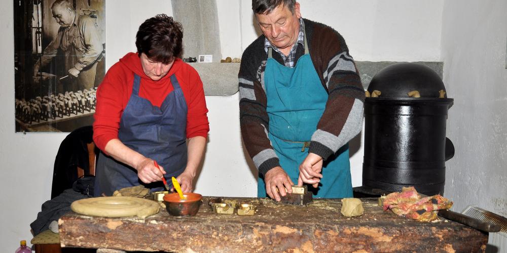 Preparing the mould before pressing. On the left, a pipe-maker is oiling the mould. On the right, he is modelling the clay in the mould. – © Lubo Lužina Preparing the mould before pressing. On the left, a pipe-maker is oiling the mould. On the right, he is modelling the clay in the mould. – © Lubo Lužina