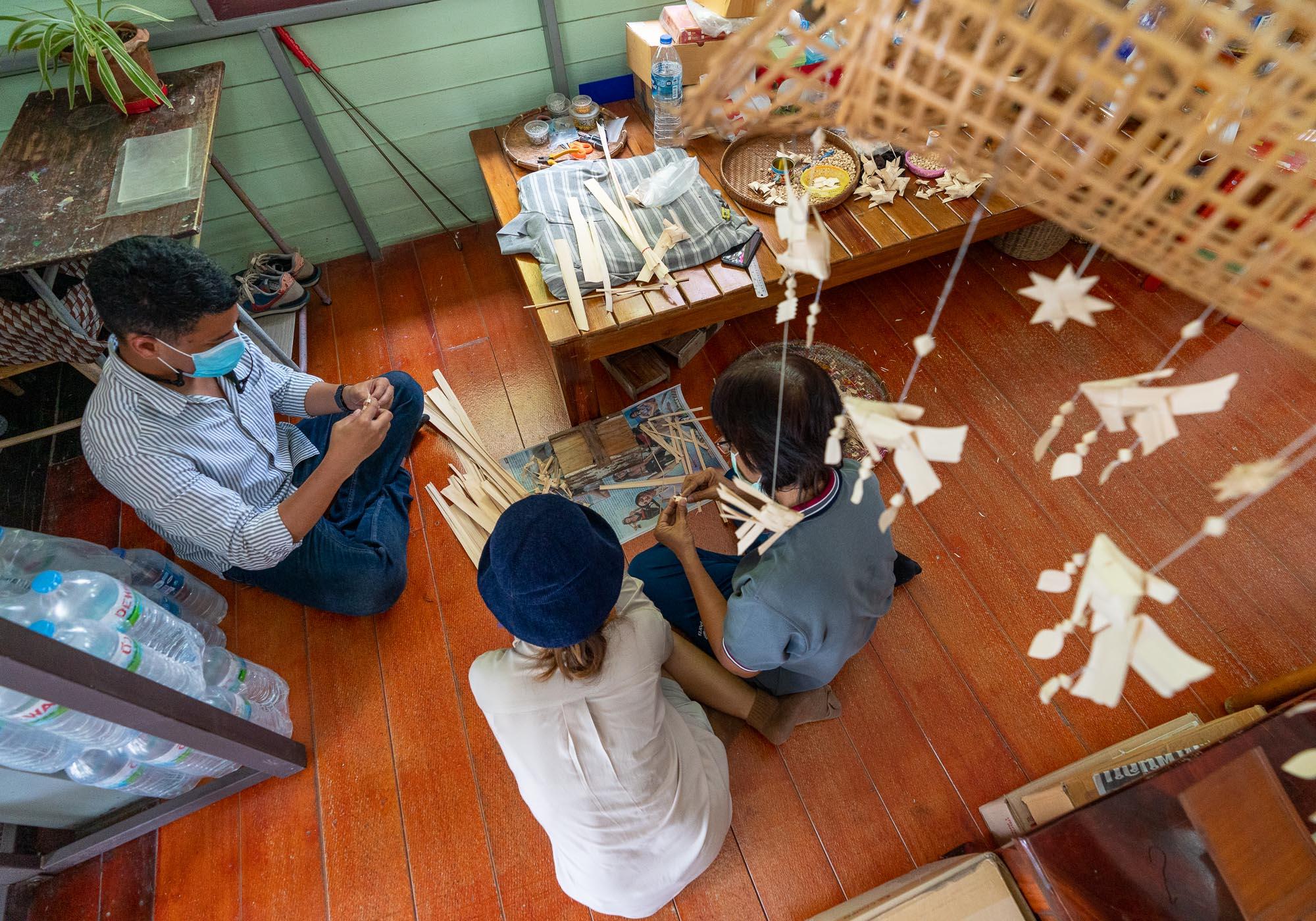 Learning to make the fish mobiles underneath one hanging in the store. – © Michael Turtle