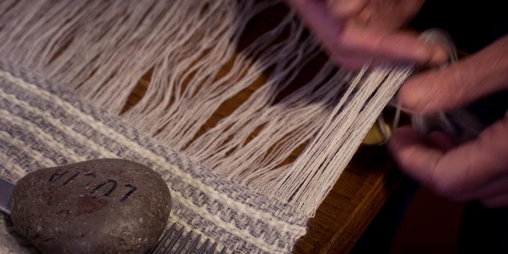 Ancient and modern skills abound in San Gimignano's historic centre. Pictured: an artisan working fabric with the loom. – © A. Miserocchi / Italian Stories