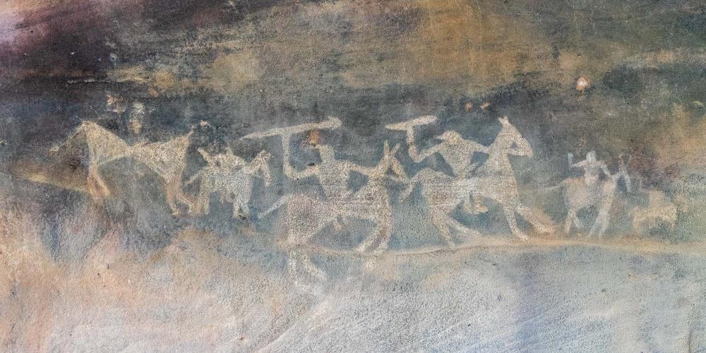 This white painting at Bhimbetka shows warriors or hunters riding on horses, holding spears in their hands in an attack stance. – © Michael Turtle