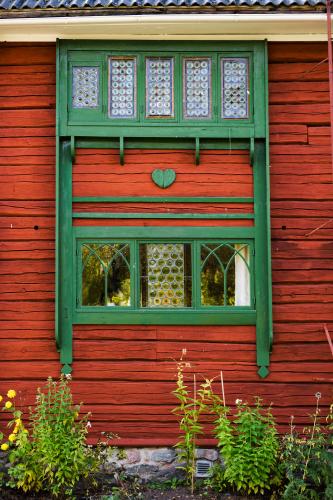 The home of Carl Larson is equally beautiful on the outside. Leaded-glass windows framed by green decorations. The heart is a recurring symbol all over the house. – © Carl Larsson-gården