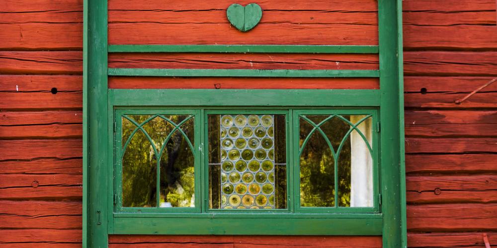 The home of Carl Larson is equally beautiful on the outside. Leaded-glass windows framed by green decorations. The heart is a recurring symbol all over the house. – © Carl Larsson-gården