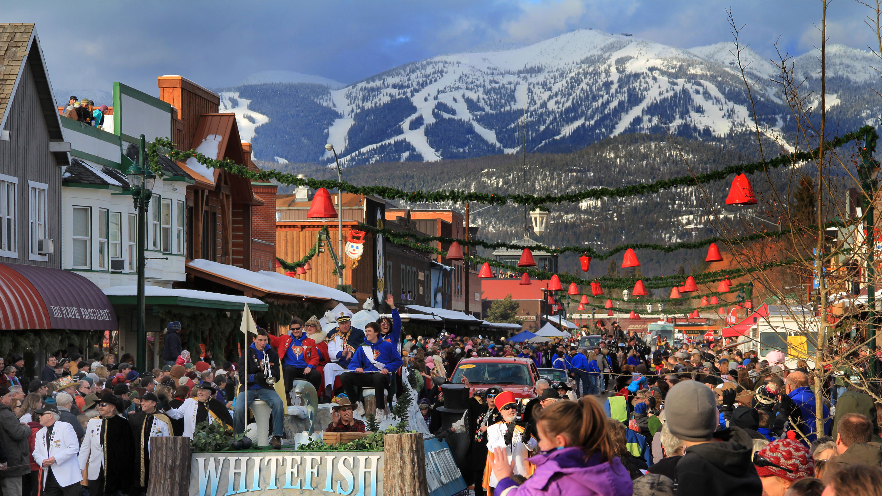 The annual Whitefish Winter Carnival Parade on Central Avenue with Big Mountain in the background.