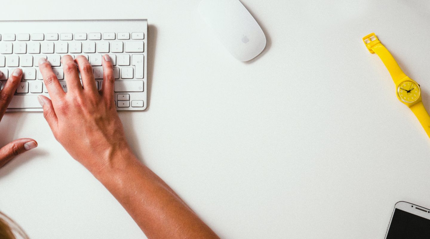 Hands typing on a white keyboard. 