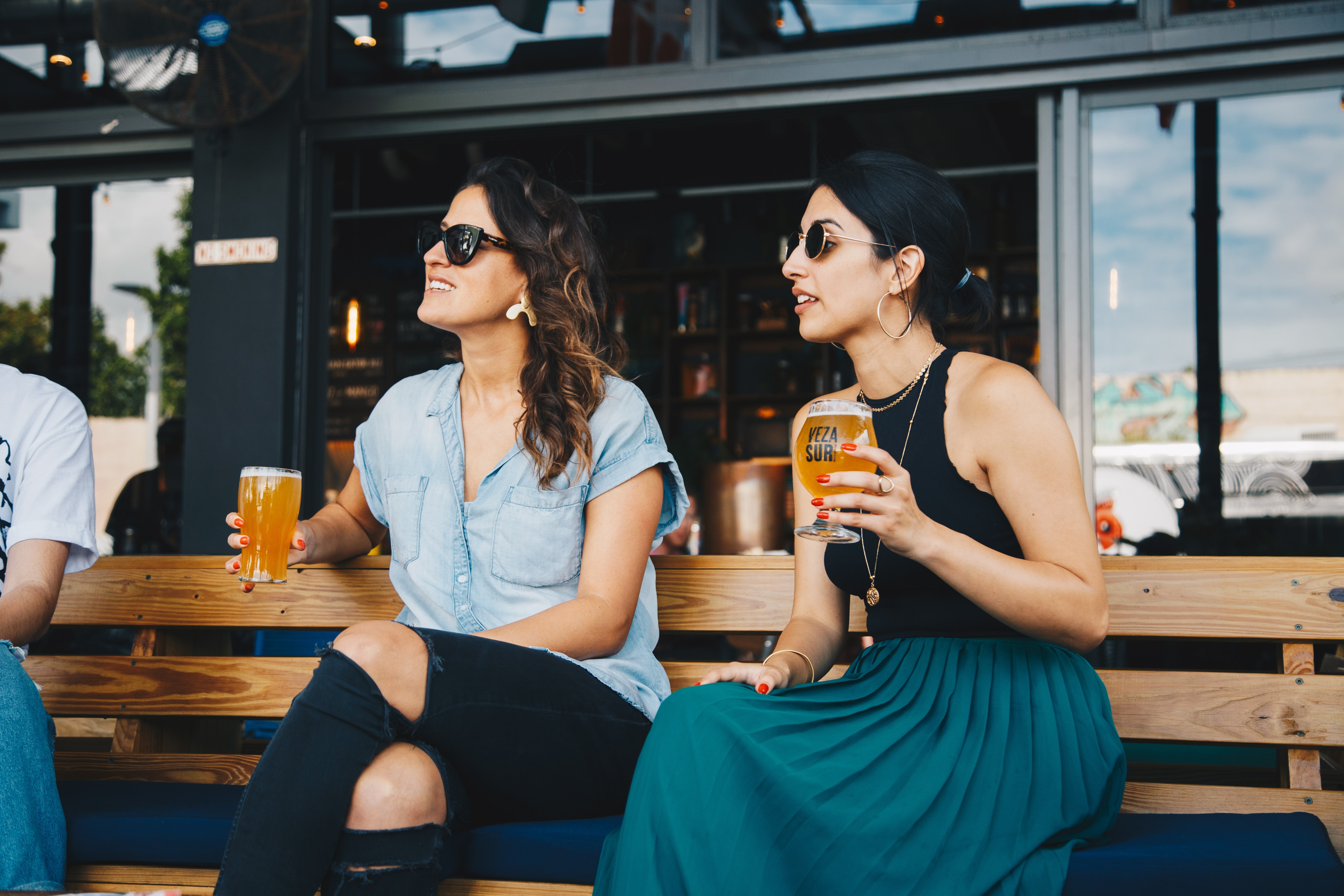 Two nicely dressed women enjoying drinks and food at a restaurant. 