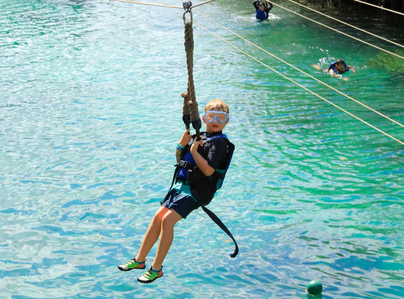 Small boy riding a zipline above a river