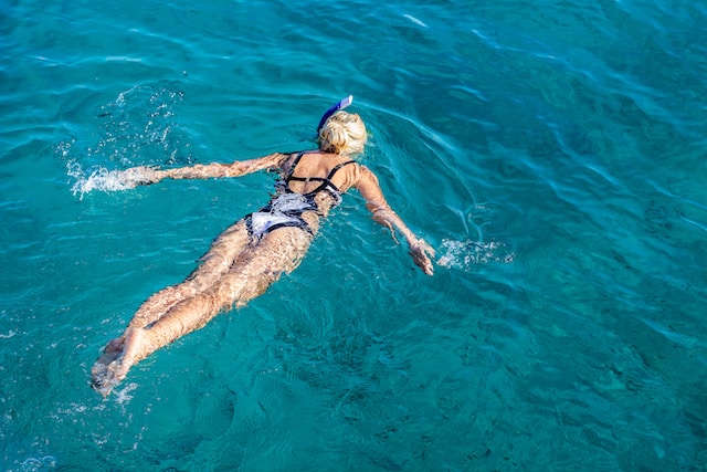 A woman snorkeling in blue waters.