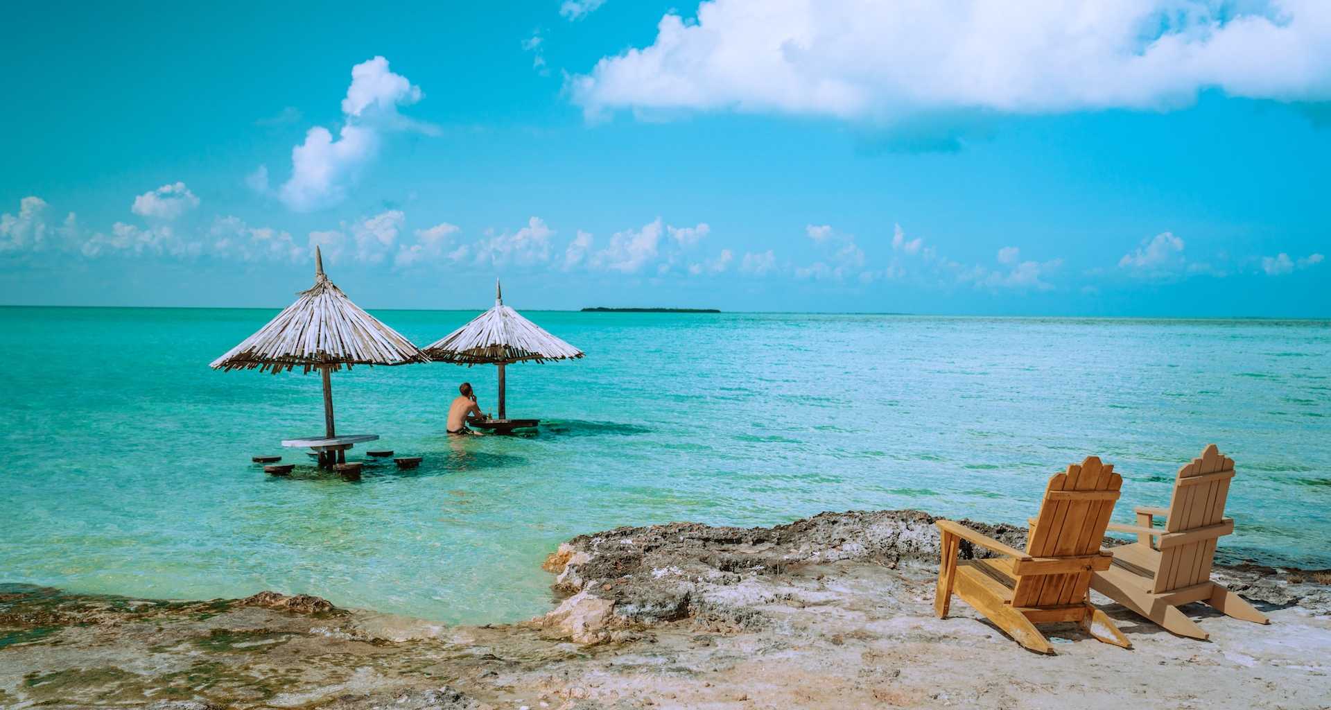 two cabanas with man underneath in the Caribbean sea