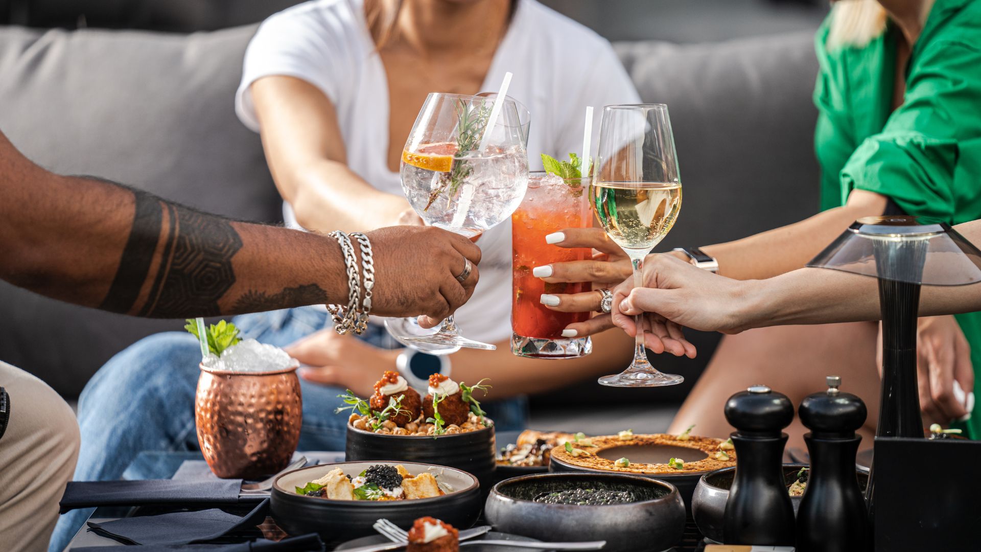 Three people, a man and two women, toasting over a table full of food