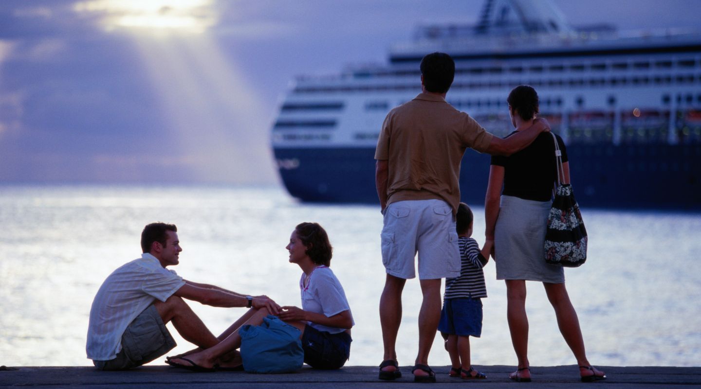 Family standing on the pier looking at a cruise. 