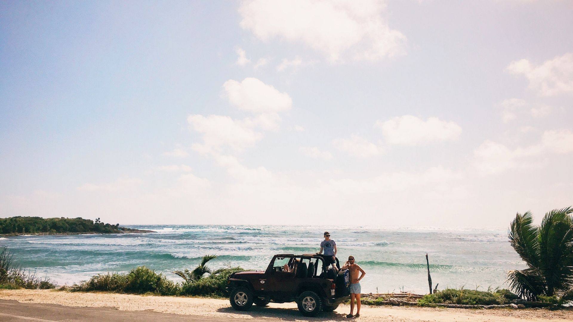 people on jeep with ocean in background