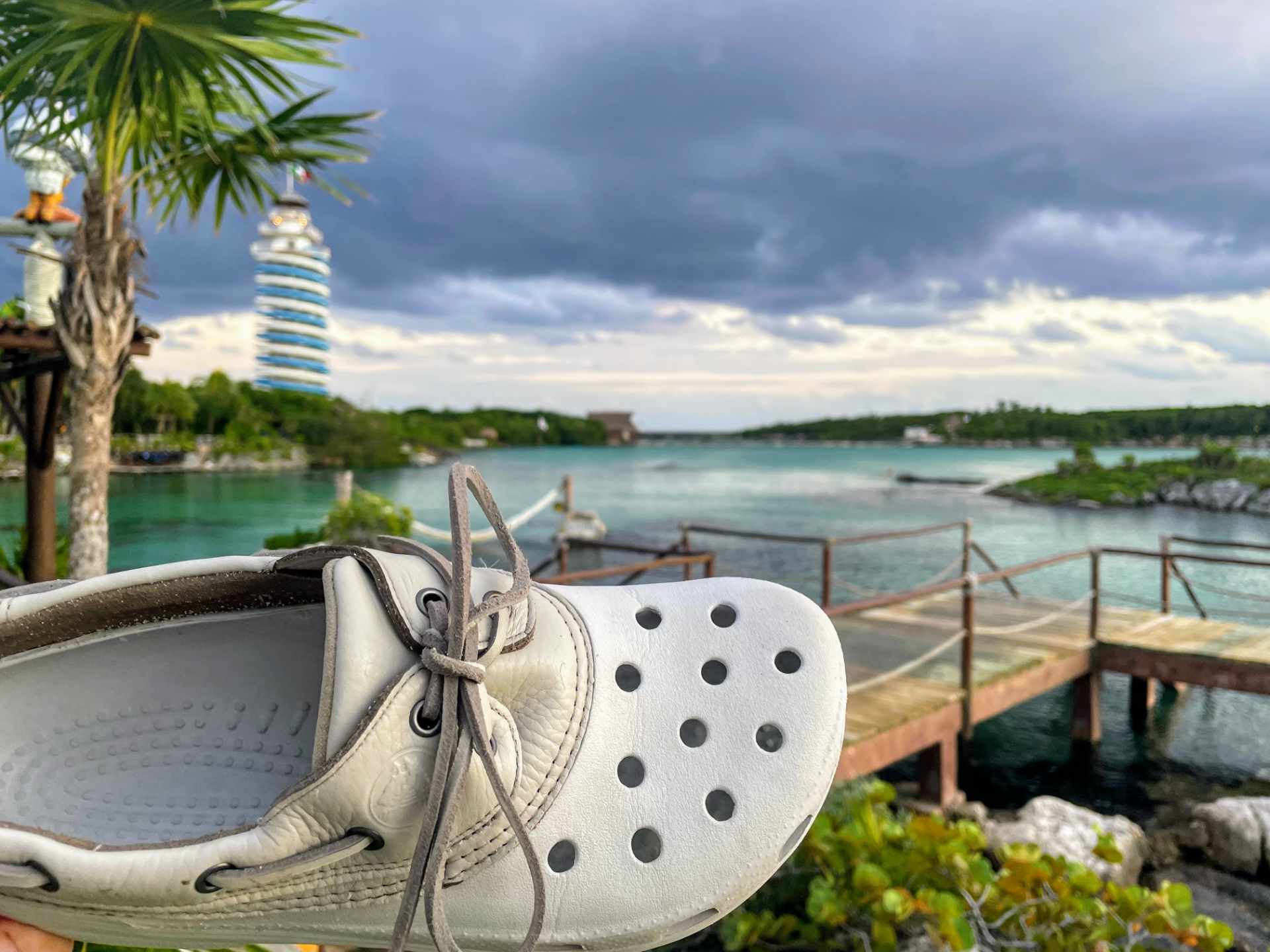 White crocs being held in front of Xel-Ha's tower.