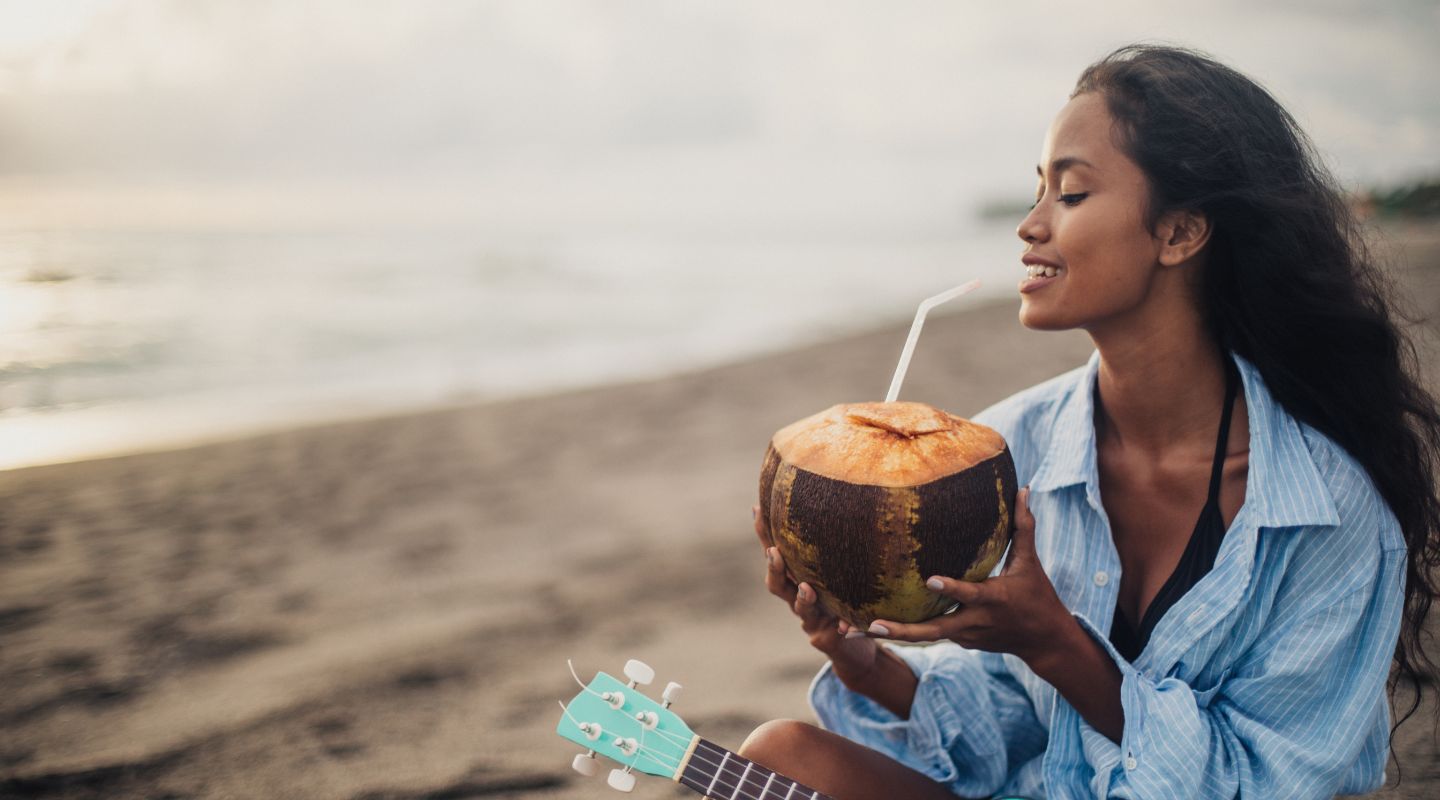 A woman drinks from a coconut. 