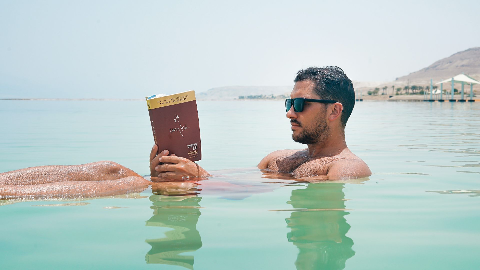 A man reads a book as he floats on the ocean