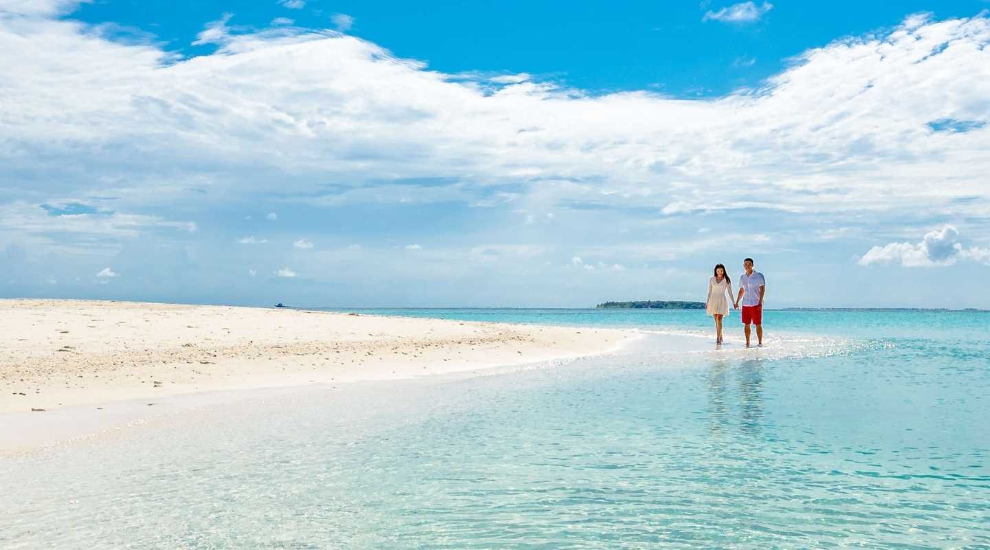 Couple holding hands, walking down the beach. 