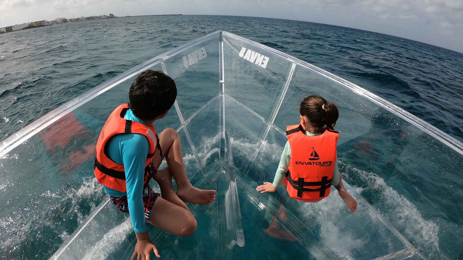 kids looking into water through glass boat