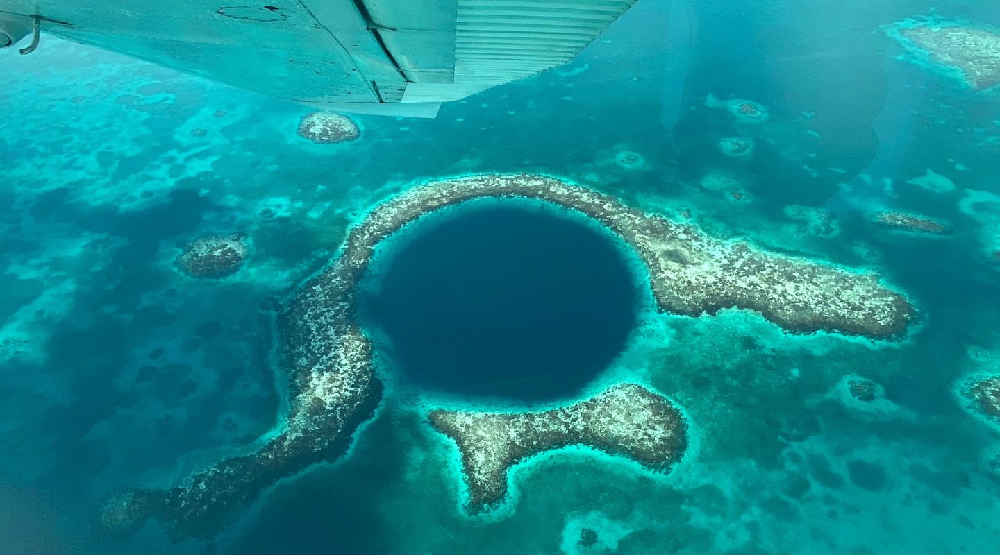 Aereal view of the blue hole, with the wing of a small plane peeking on one corner of the photo.