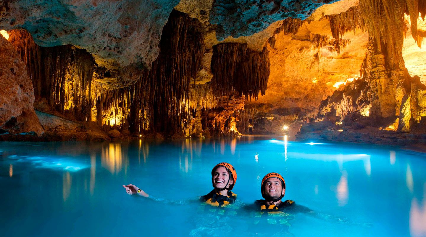 A couple swimming inside a well-lit cave