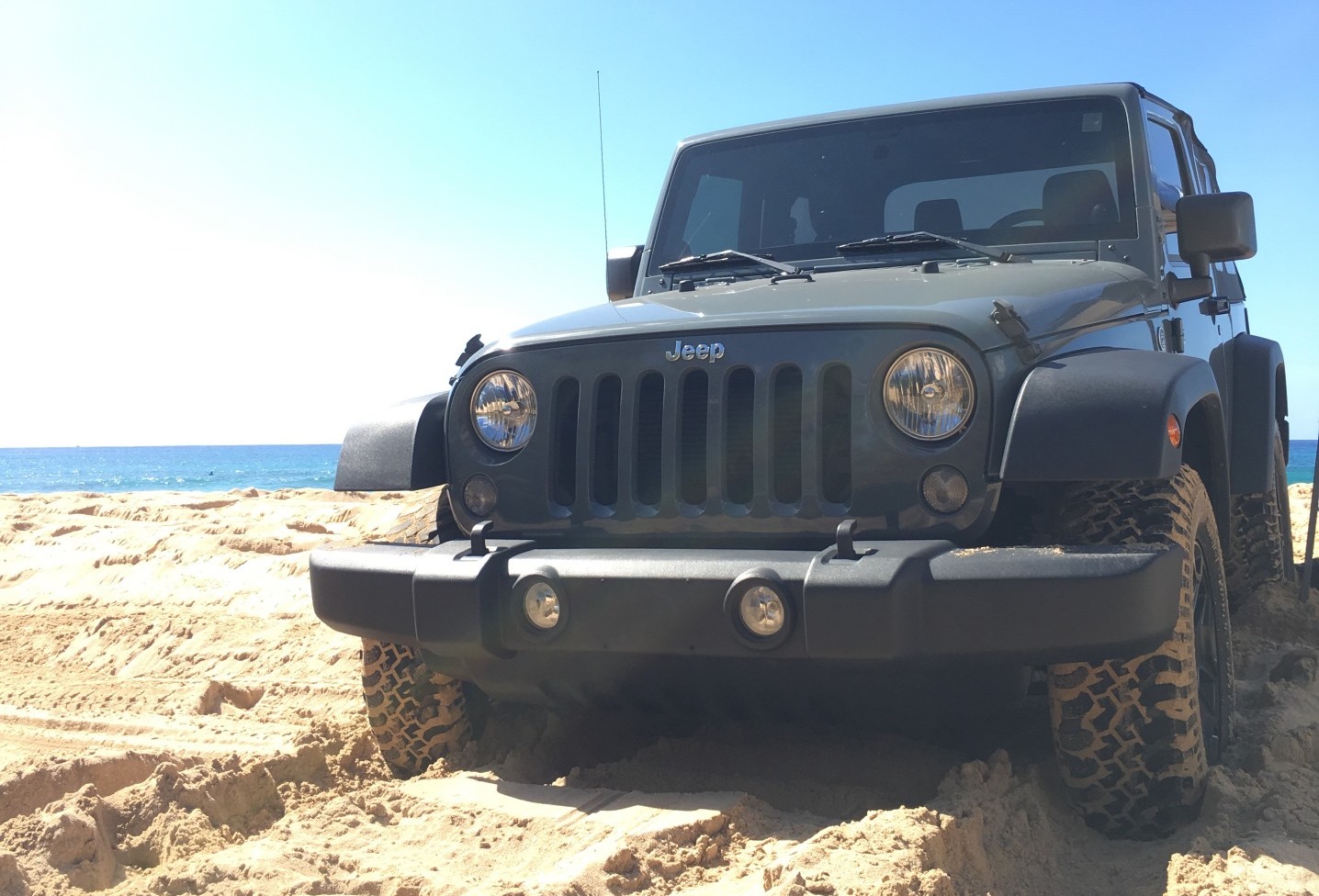 jeep in sand with sea in the background