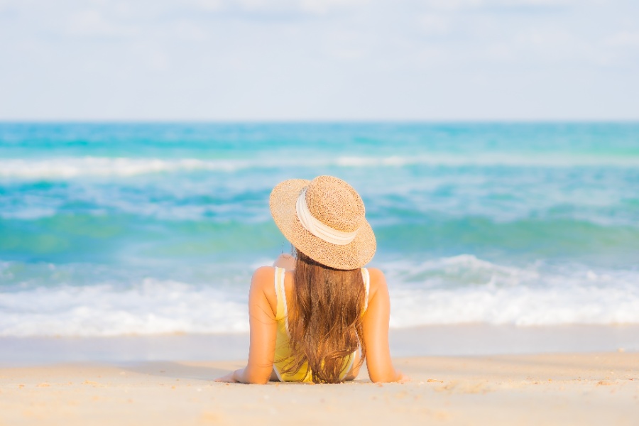 A girl is sitting on the white sand on the beach