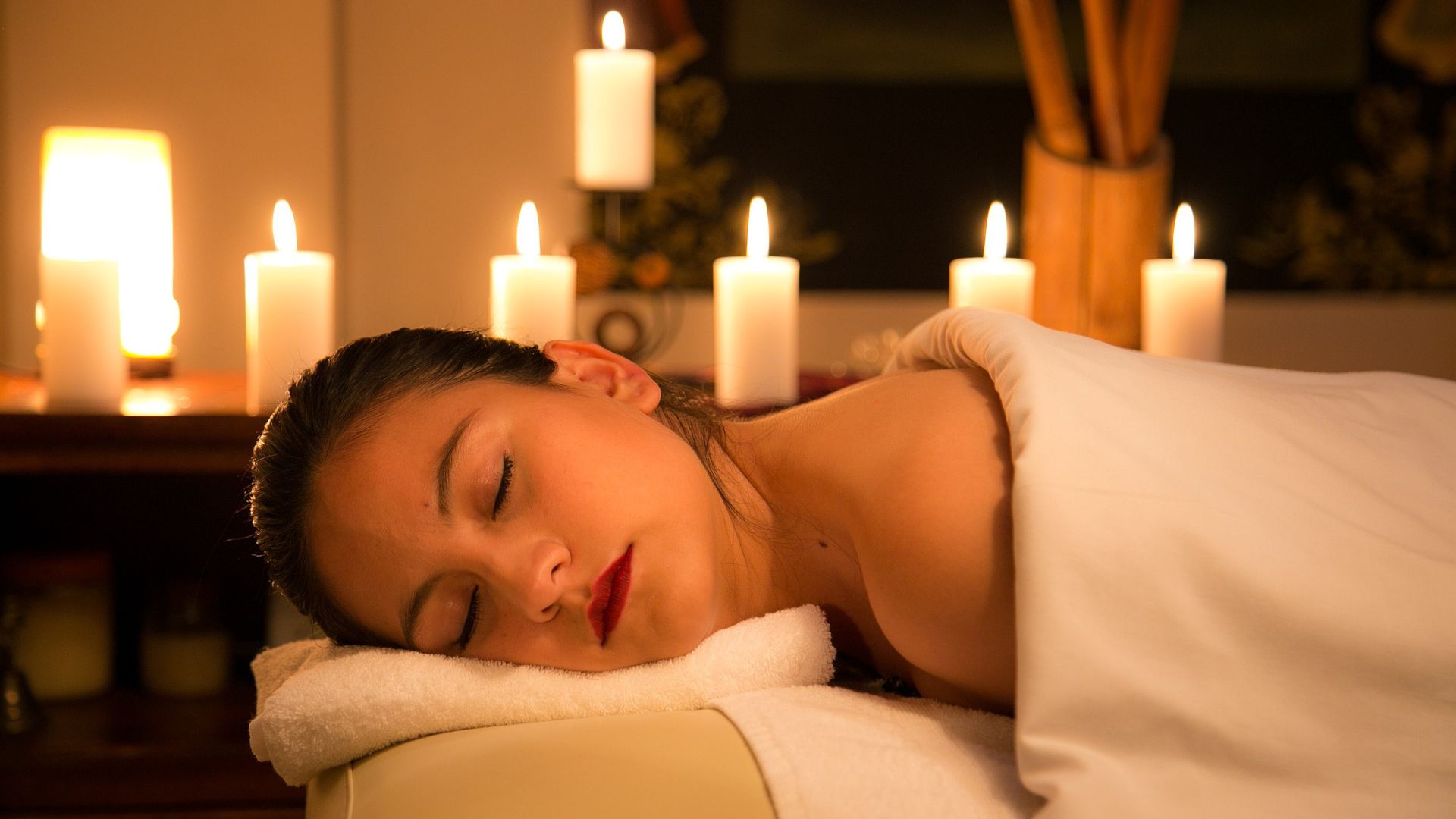 A woman getting a massage surrounded by candles
