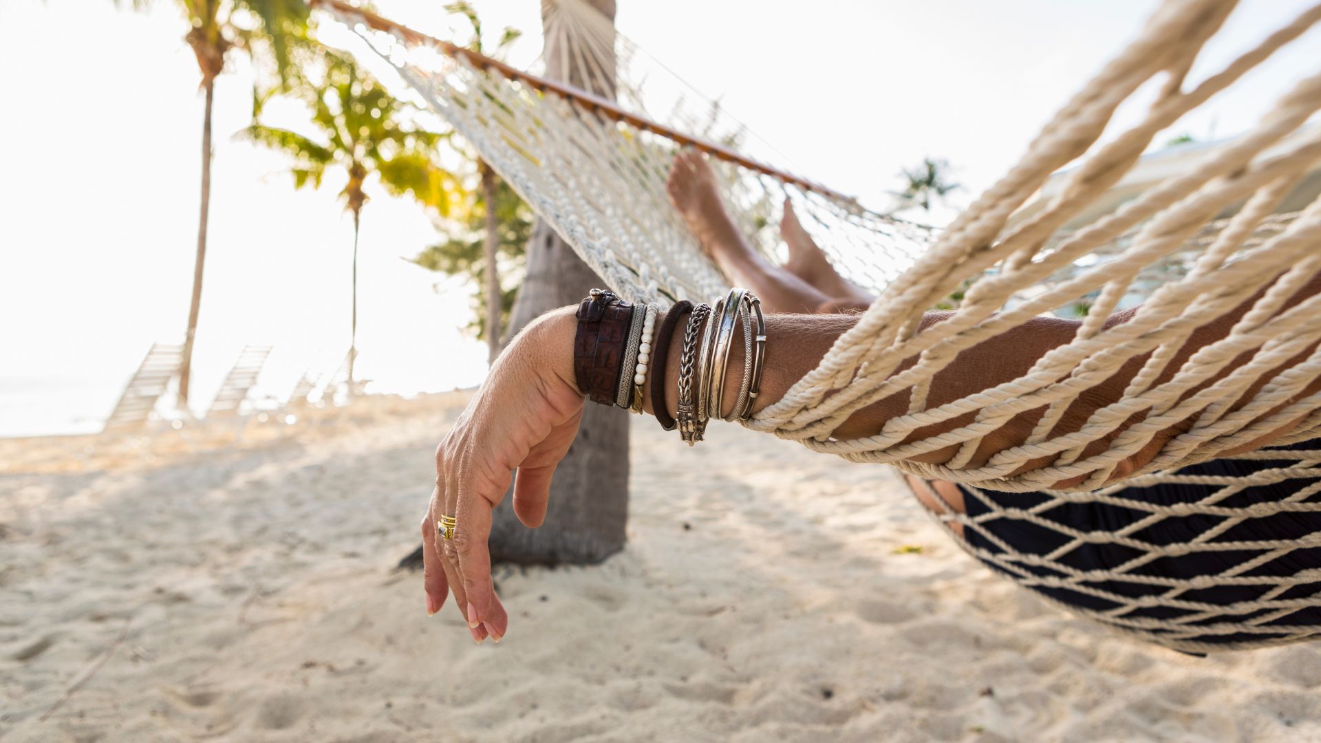 A forearm hanging off the side of a hammock.